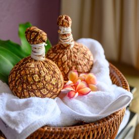 Thai massage with herbal hot compress ball on wooden tray